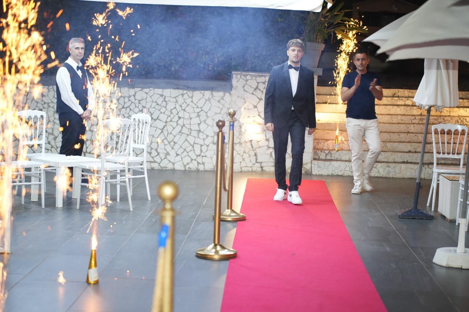 Un uomo in giacca e cravatta sta camminando su un tappeto rosso