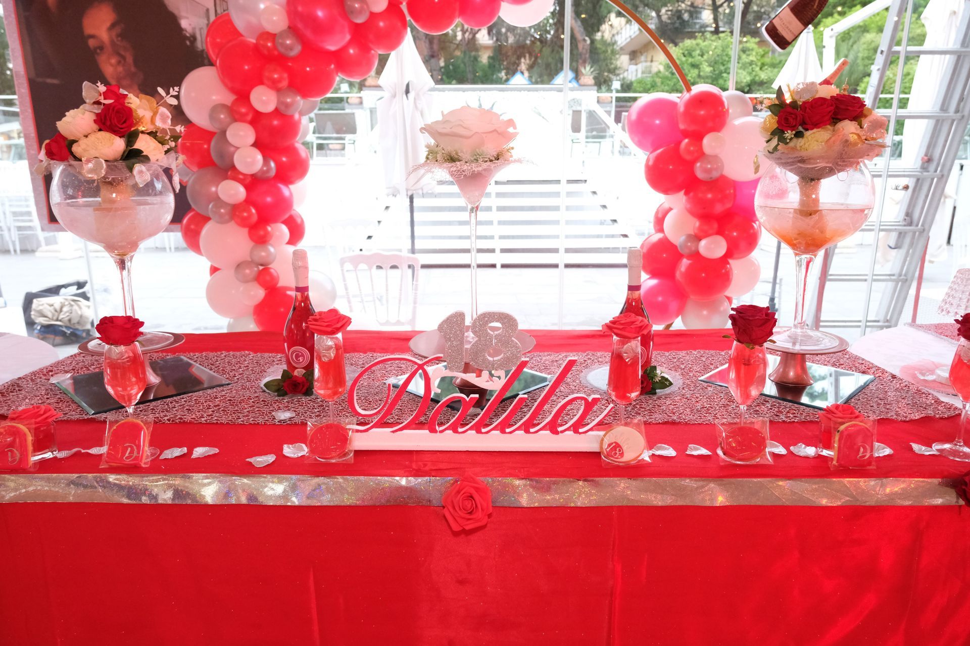 Un tavolo con palloncini, fiori e bicchieri di vino sopra.