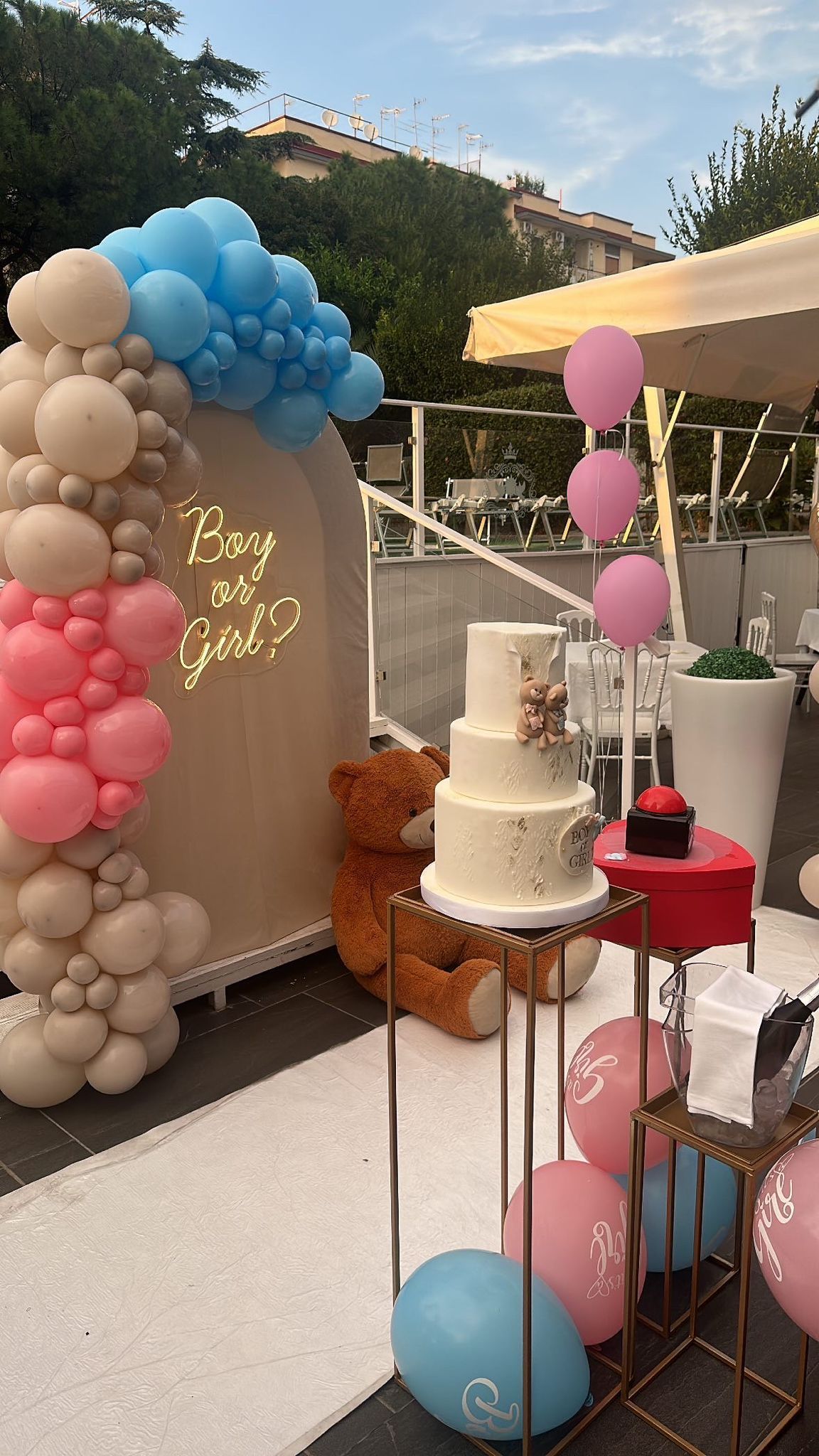 Una torta è appoggiata su un tavolo con dei palloncini e un orsacchiotto.