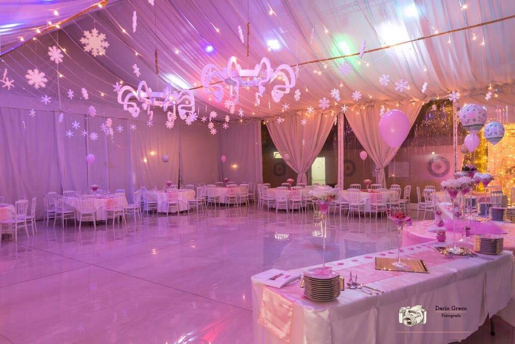 Una grande stanza con tavoli, sedie e luci viola appese al soffitto.