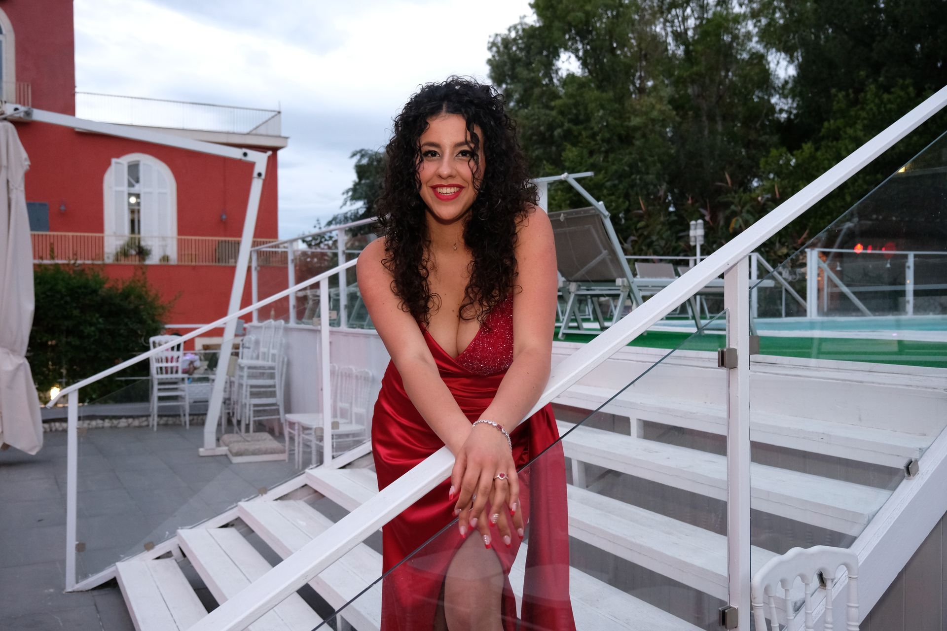 Una donna con un vestito rosso è in piedi su una rampa di scale bianche.