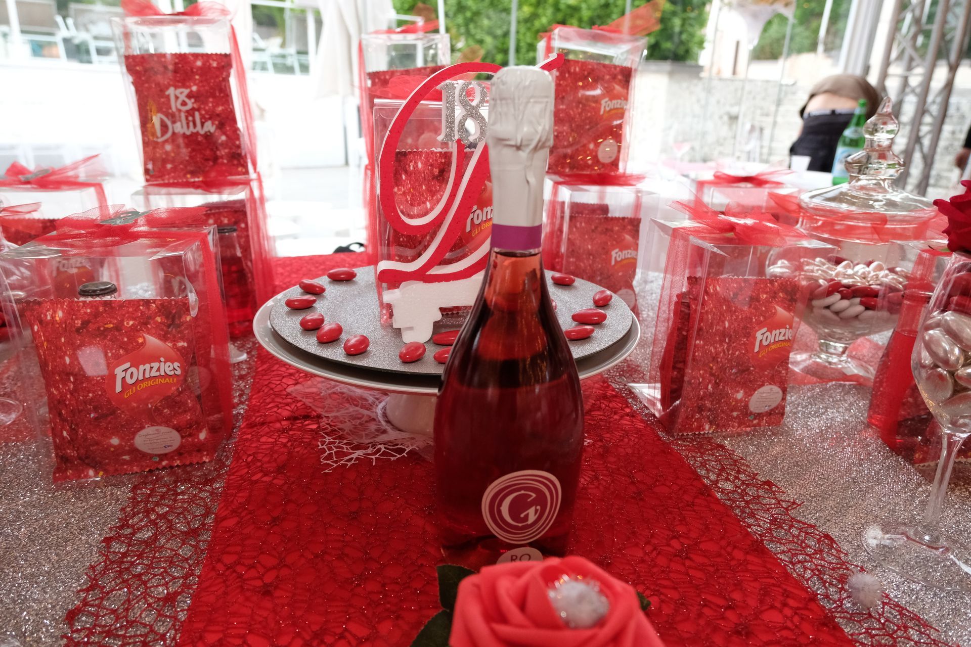 Una bottiglia di vino è appoggiata su un tavolo accanto a una rosa rossa.