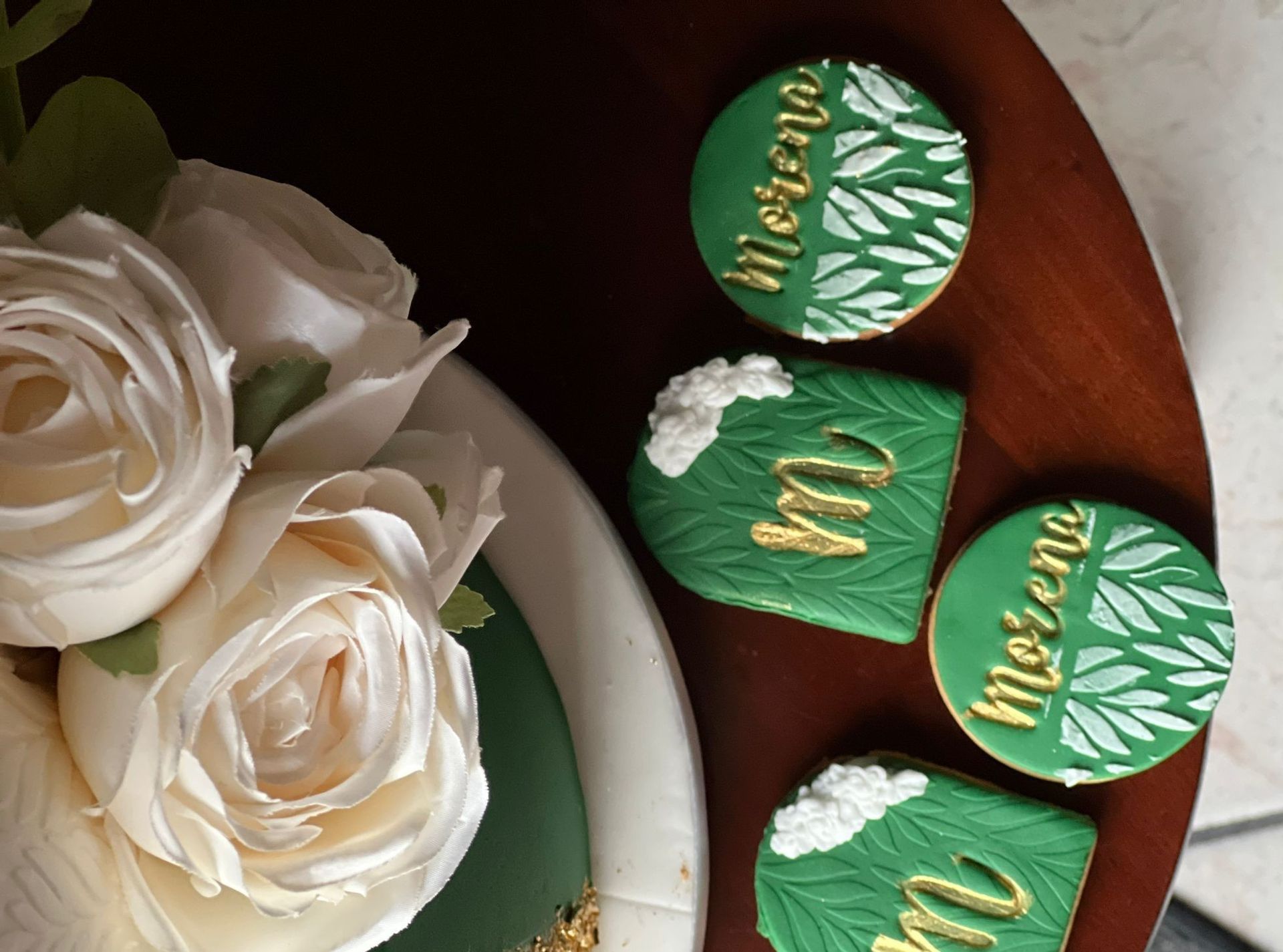 Una torta con rose bianche e biscotti verdi che dicono mecena