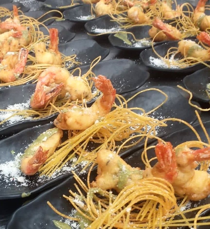 Un mucchio di piatti di cibo con gamberi e tagliatelle sopra