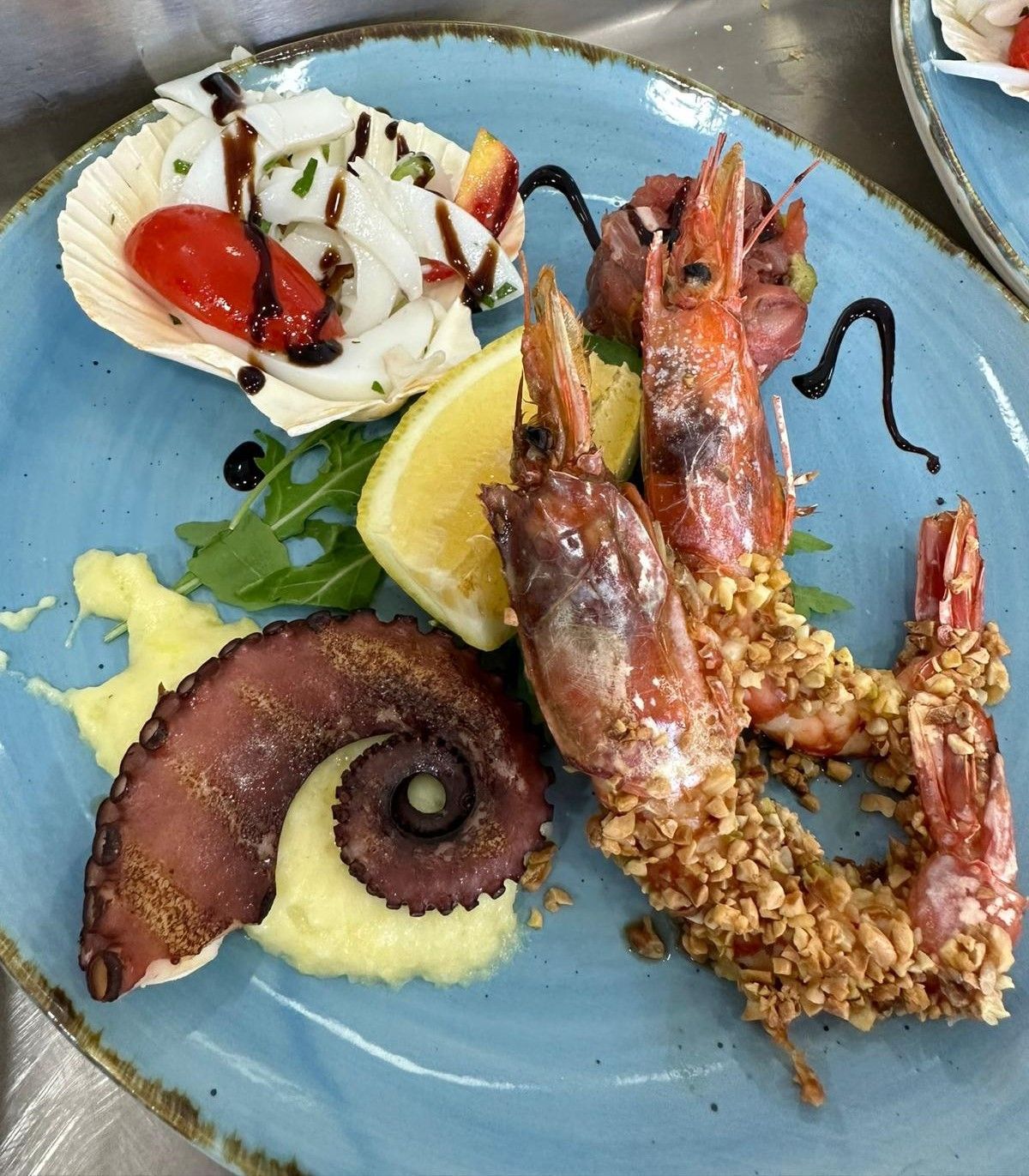 Un piatto blu condito con gamberi fritti e polpo