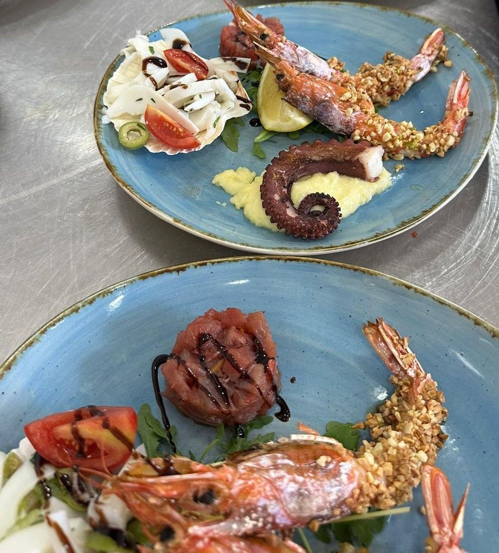 Due piatti di cibo con gamberi e polpo sopra