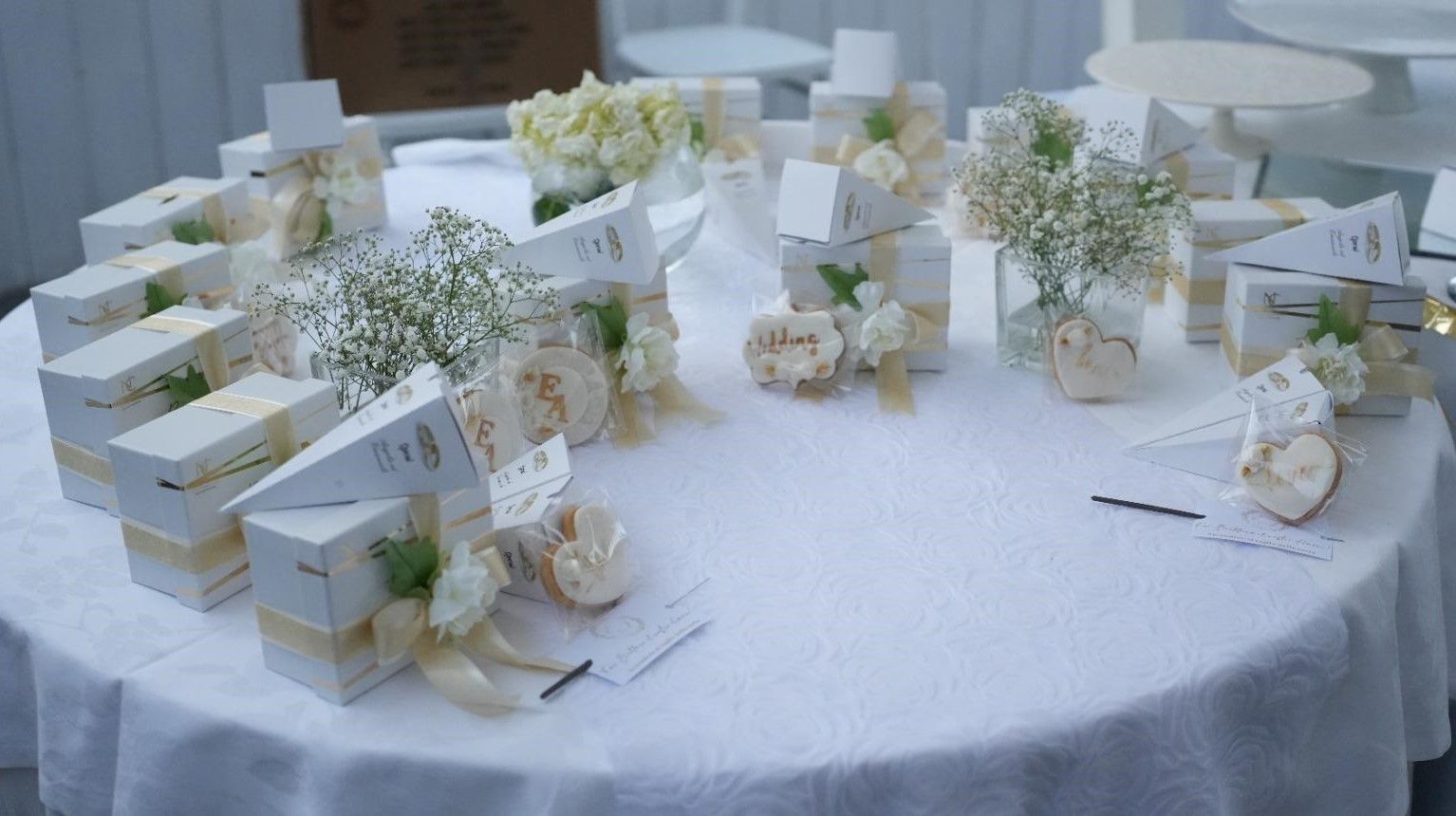 Un tavolo con una tovaglia bianca e fiori bianchi sopra.