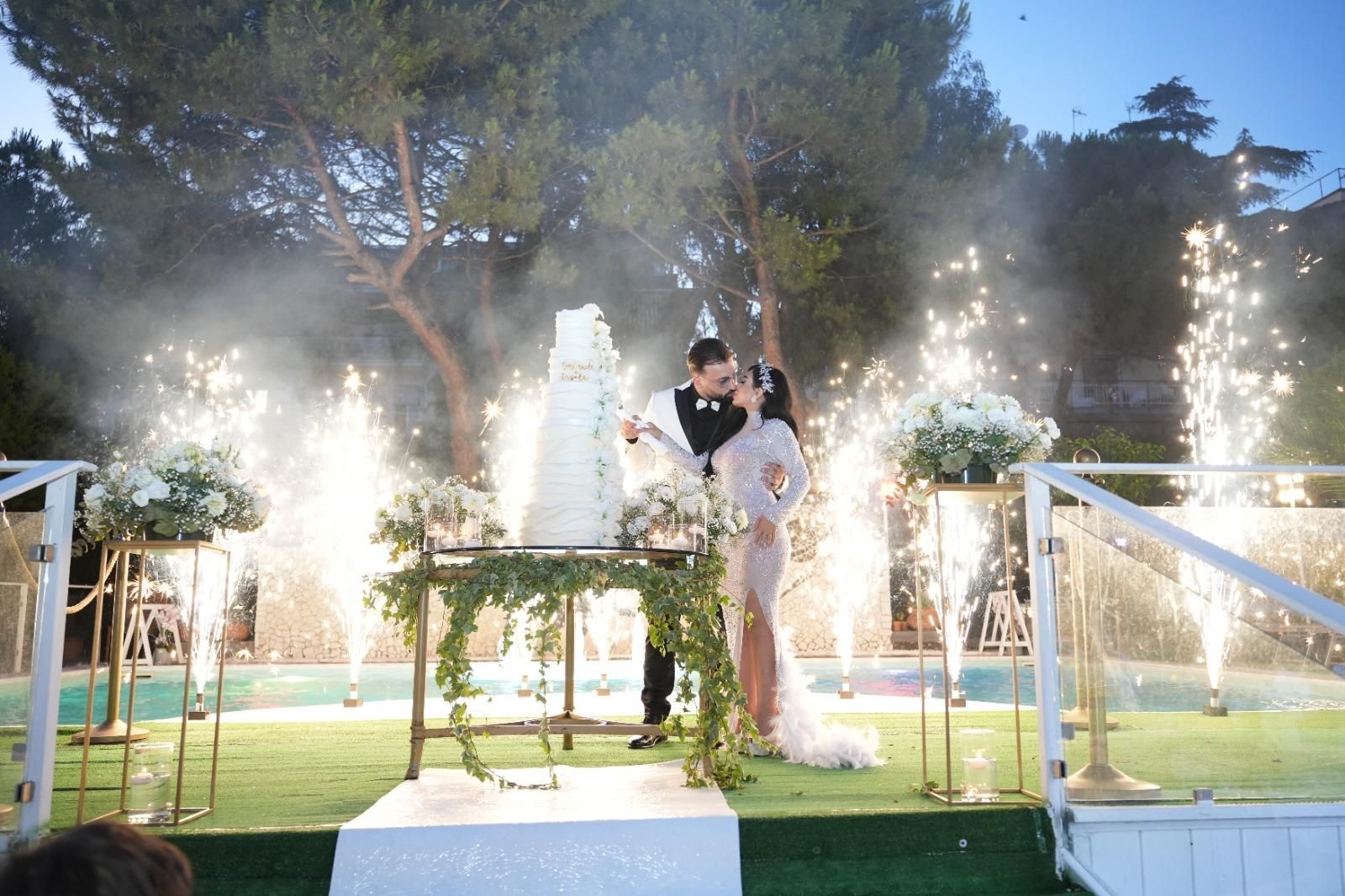 Gli sposi tagliano la torta nuziale davanti ai fuochi d'artificio.
