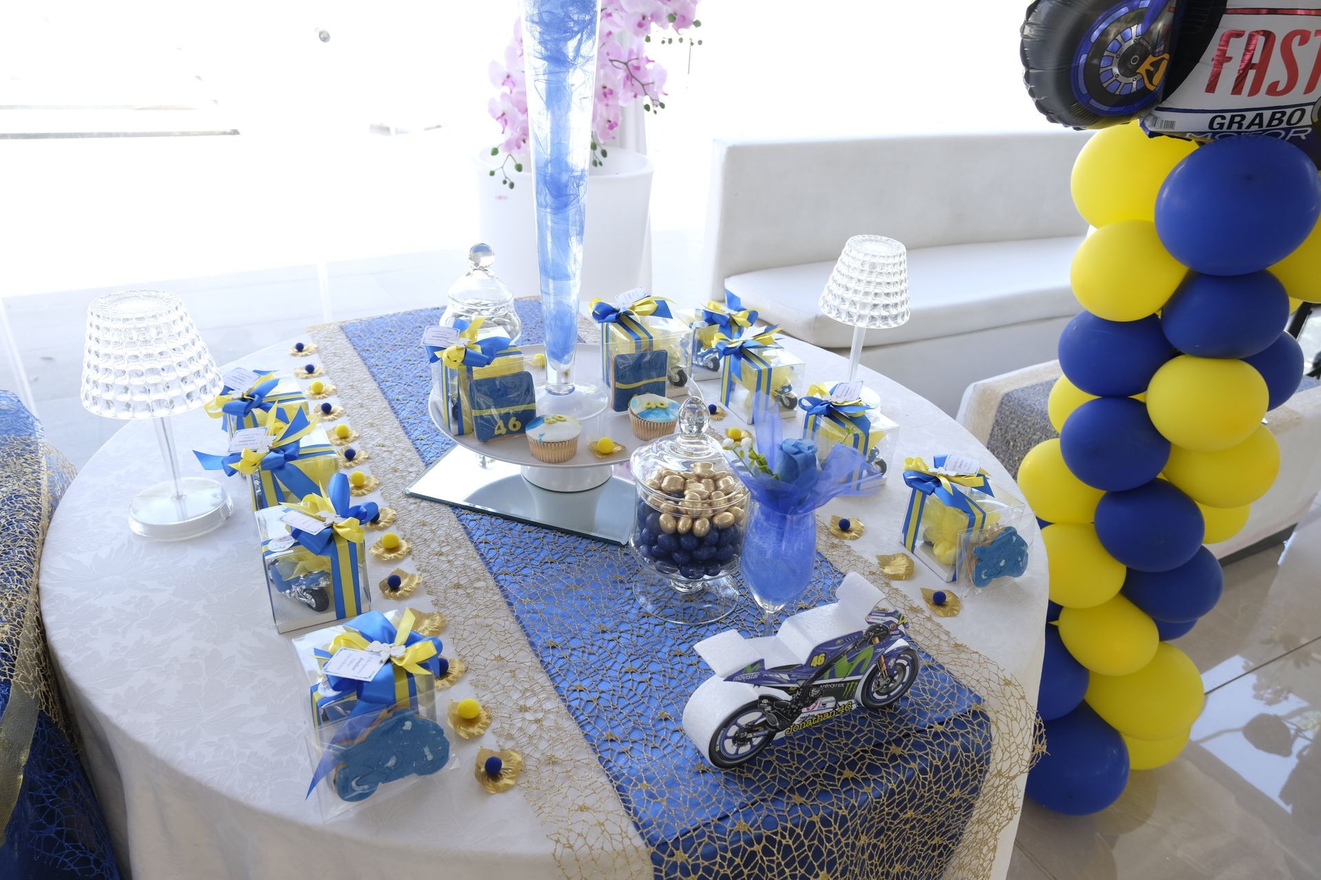 Un tavolo con palloncini blu e gialli e una motocicletta sopra