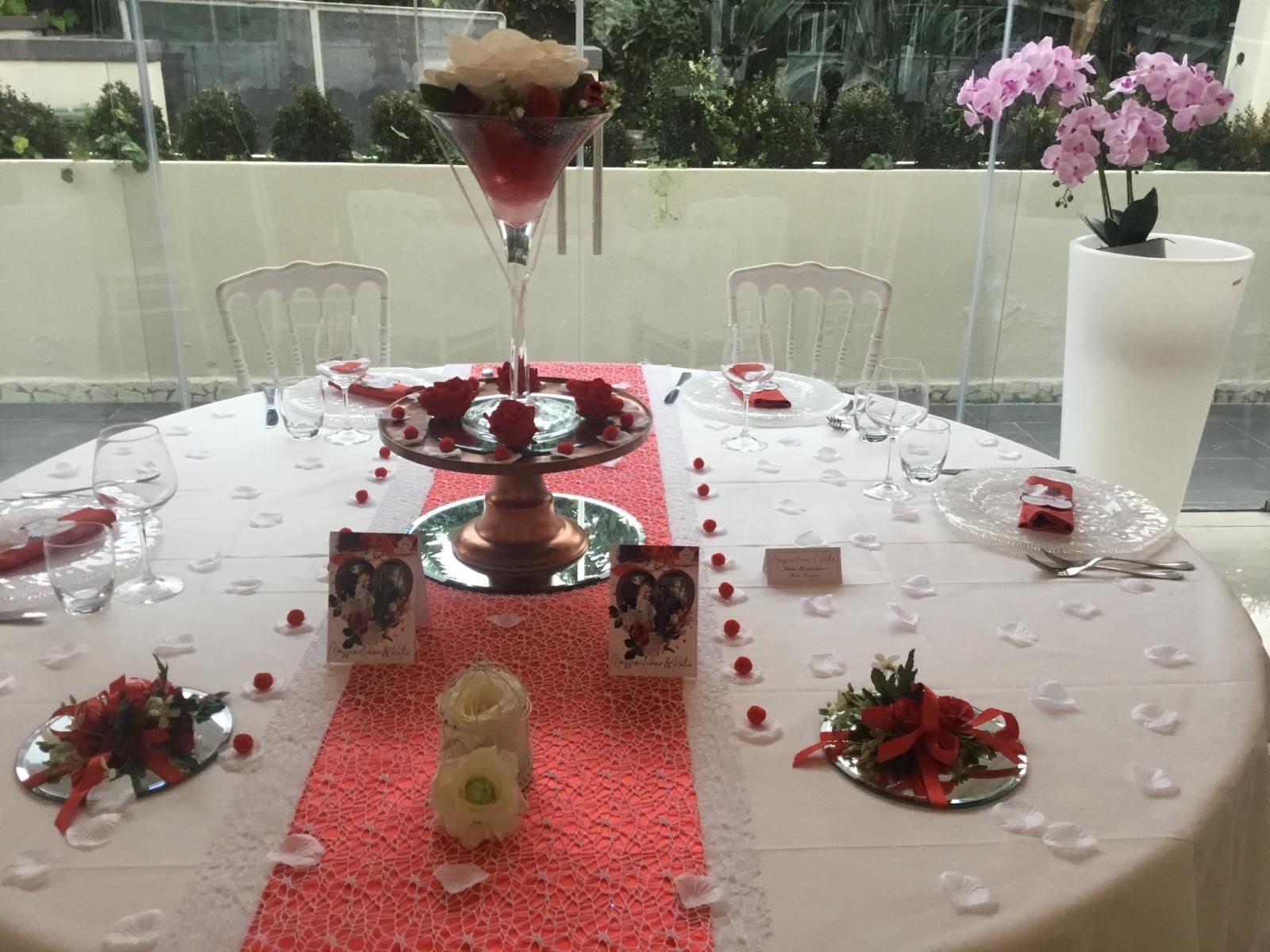 Un tavolo con un runner rosso e dei fiori sopra