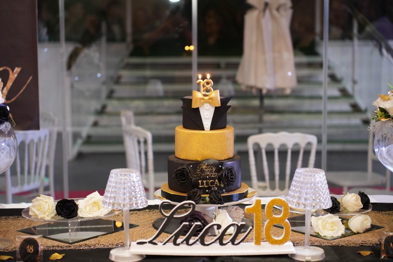 Una torta di compleanno nera e oro è appoggiata su un tavolo.