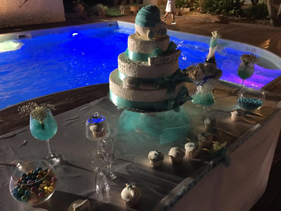 Una torta è appoggiata su un tavolo davanti a una piscina.