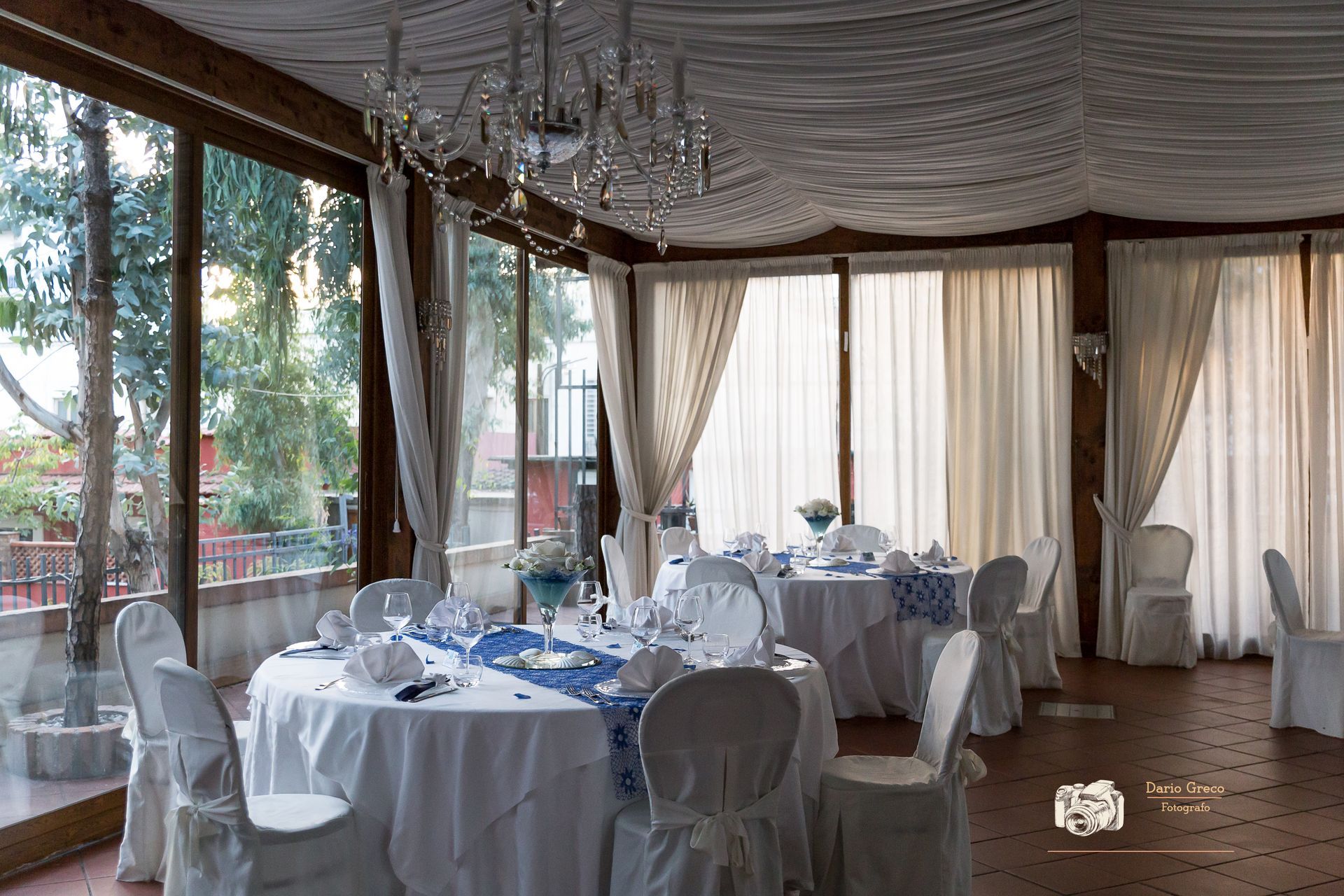 Una sala con tavoli e sedie allestita per un ricevimento di nozze