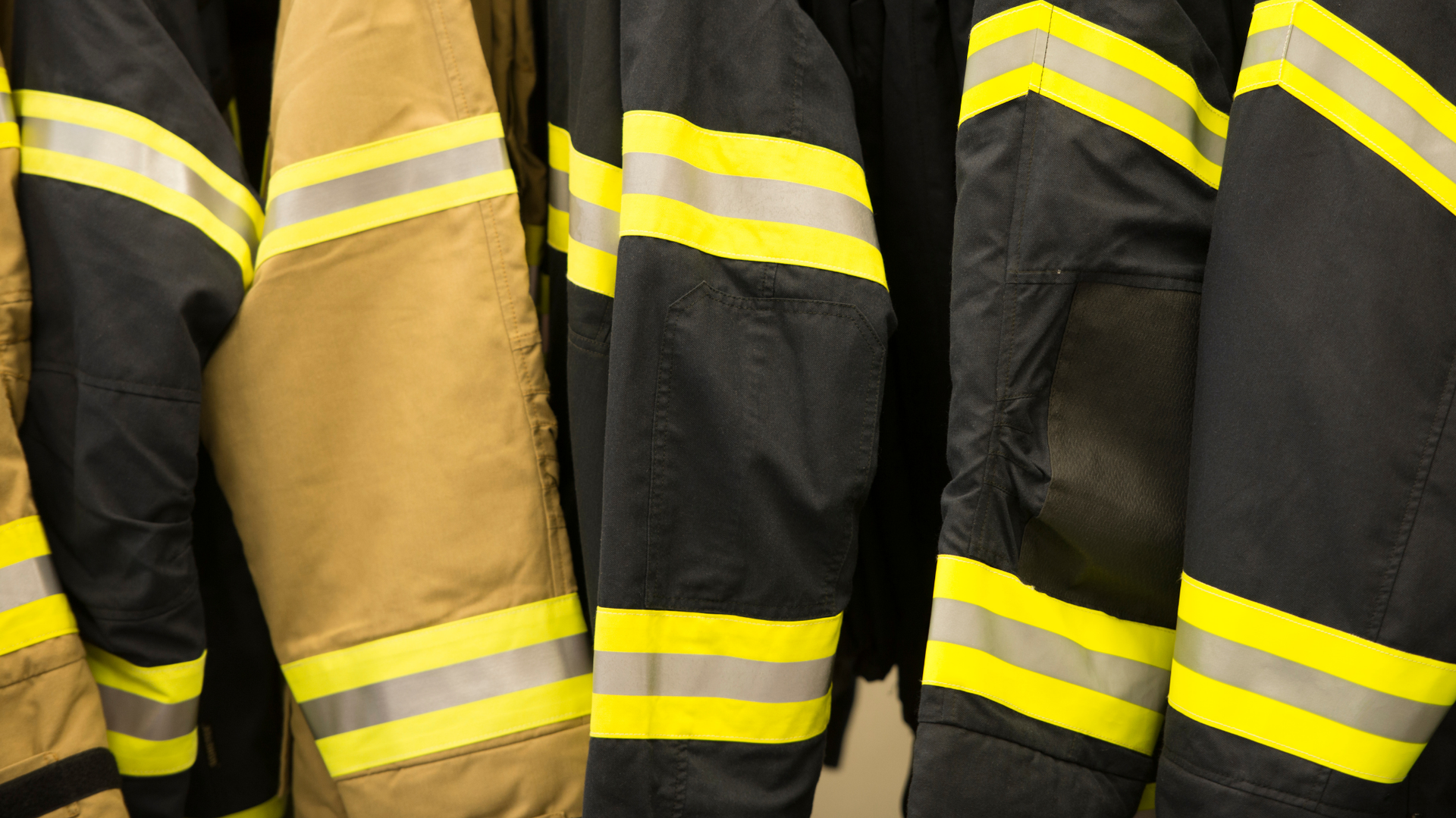 Firefighter jackets hanging, primarily black with yellow and silver reflective stripes.