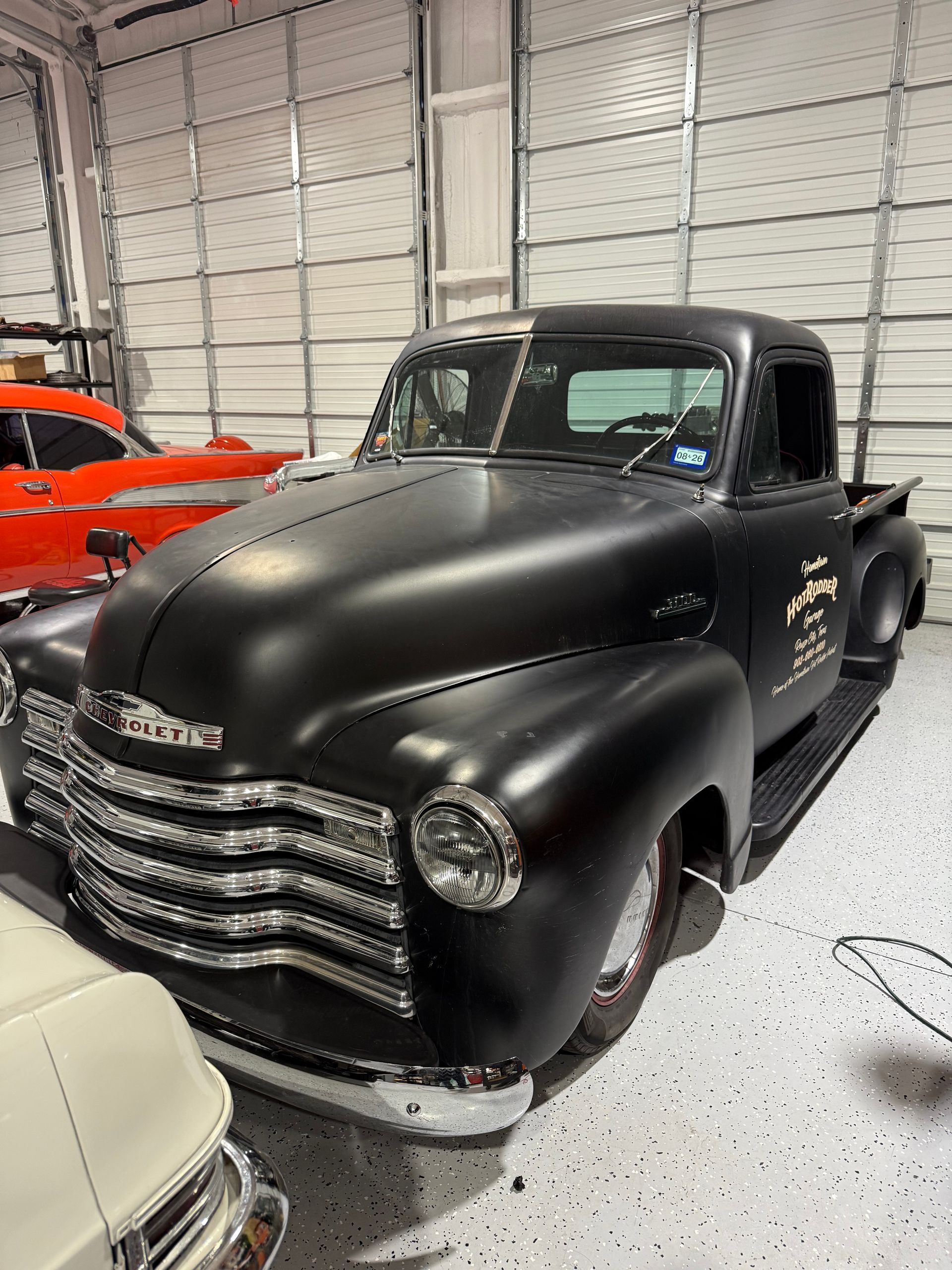 Black vintage Chevrolet pickup truck in a garage.