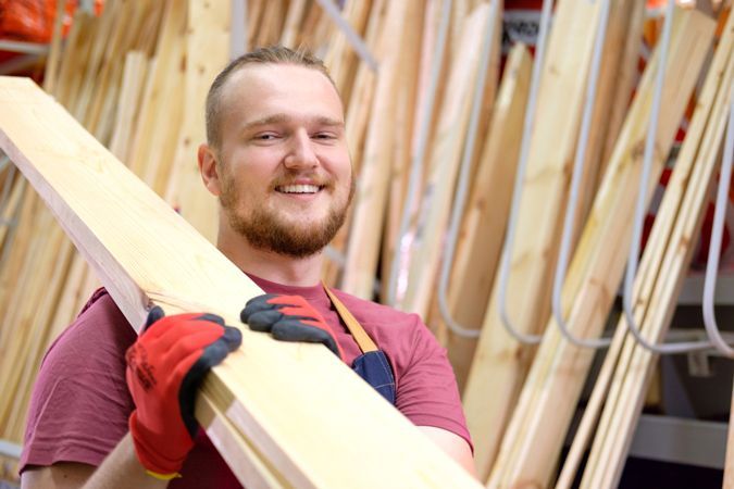 Smiling Carpenter Carrying Woods — Carpenter in Newcastle