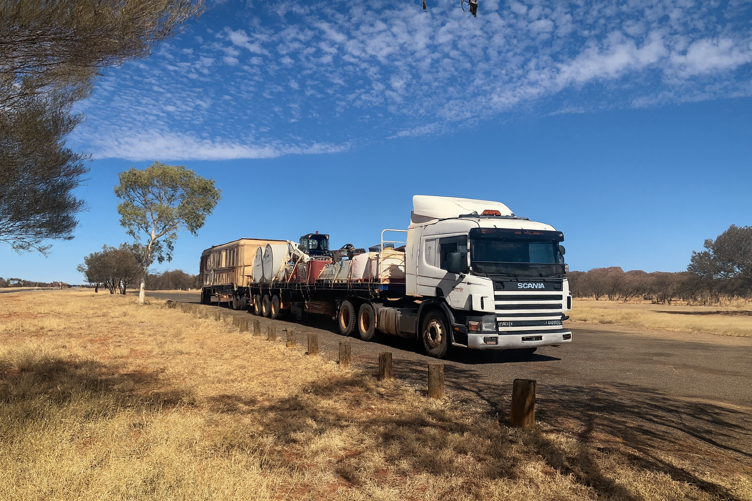 White semi-truck hauling tanks on a road, under a blue sky with clouds — Pedersen NT Pty Ltd in Ciccone, NT