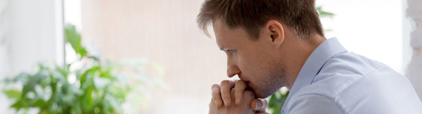 A man is sitting at a table with his hands on his chin.