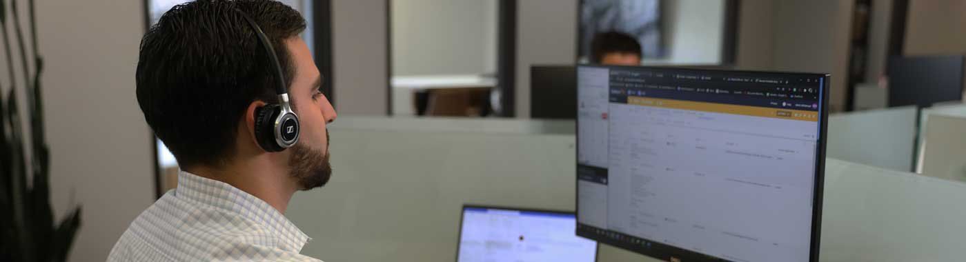 A man wearing a headset is sitting in front of a computer.