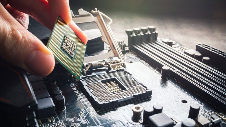 A person is holding a cpu over a motherboard.