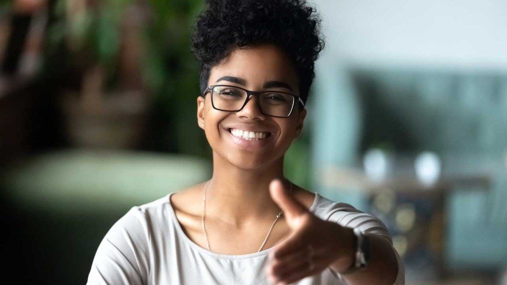 A woman wearing glasses is smiling and giving a thumbs up.