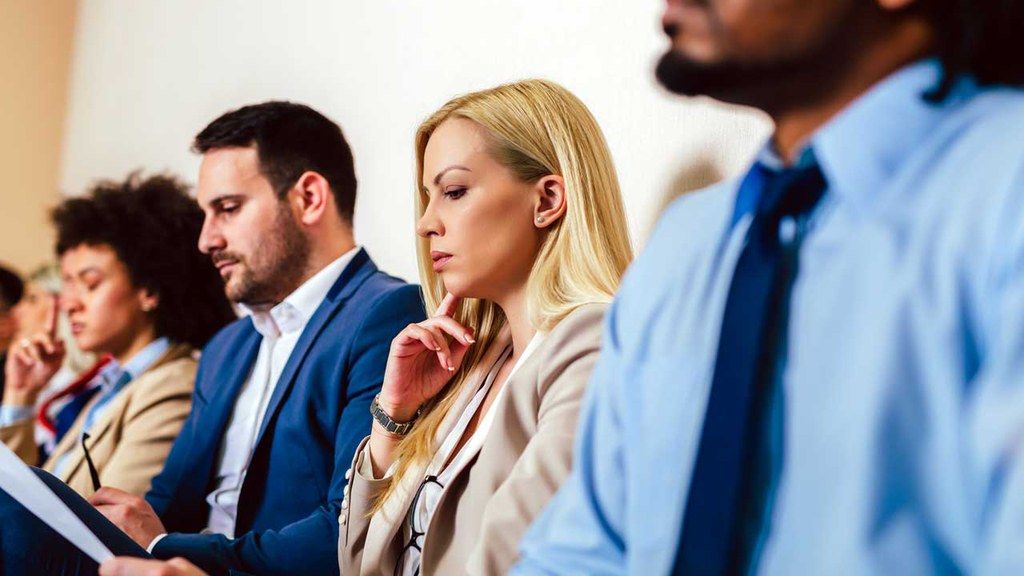 A group of people are sitting in a row at a job interview.