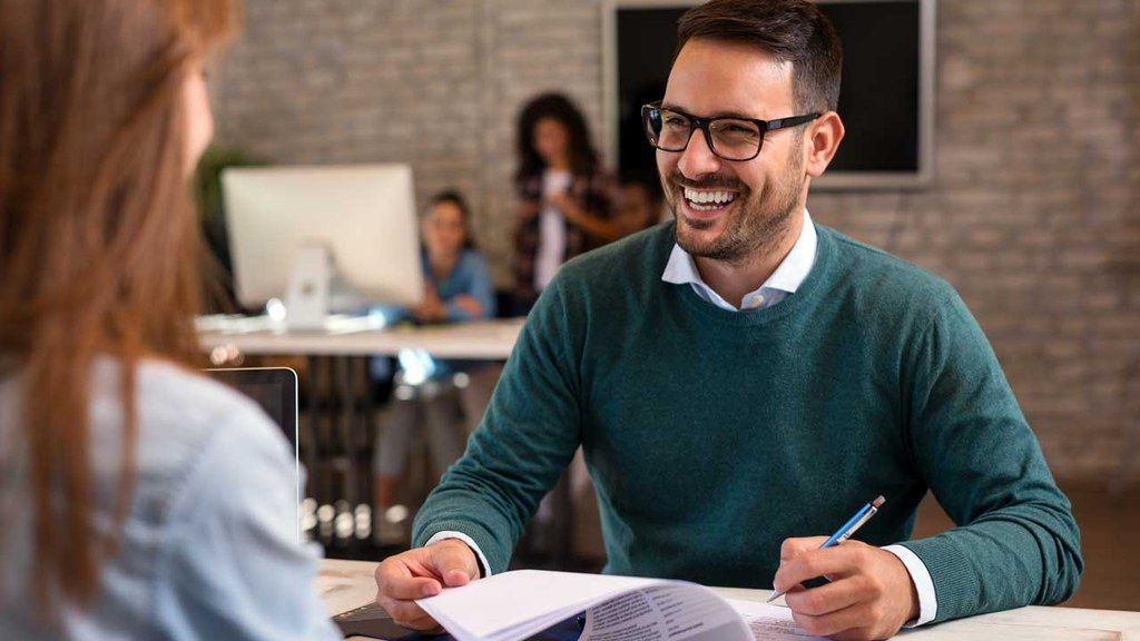 A man is sitting at a table talking to a woman.