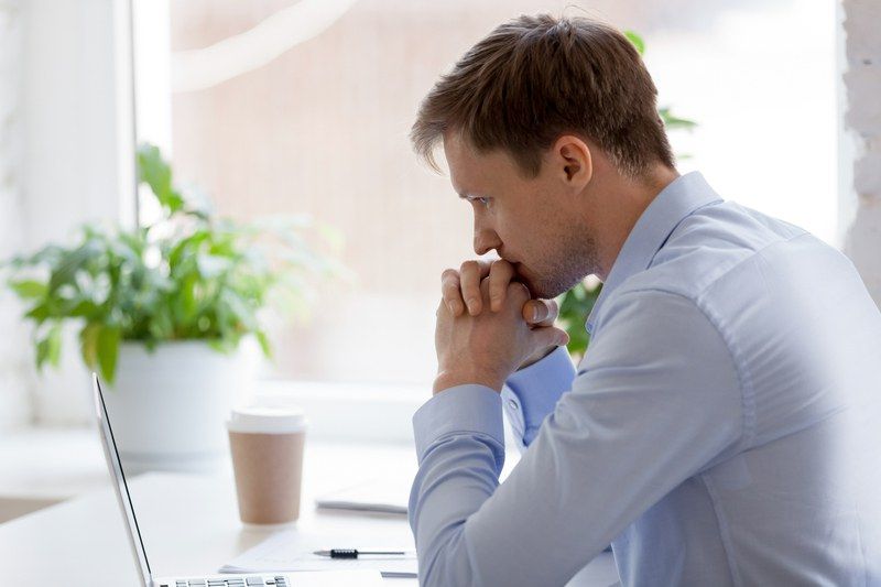 A man is sitting at a desk in front of a laptop computer.