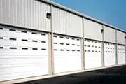 White industrial building with multiple overhead garage doors.