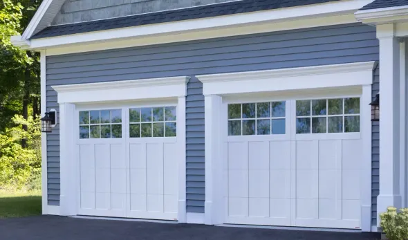 White house with a gray garage door, brown door, and brick driveway. White house with a gray garage door, brown door, and brick driveway.
