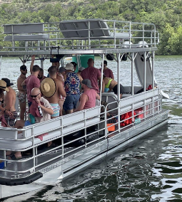 A group of people are on a pontoon boat on a lake