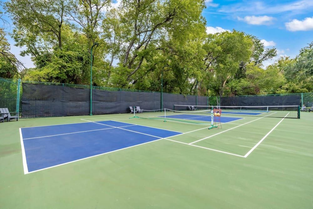 Apartment tennis court with a fence and trees in the background at Marquis at Silver Oaks in Grapevine, TX.