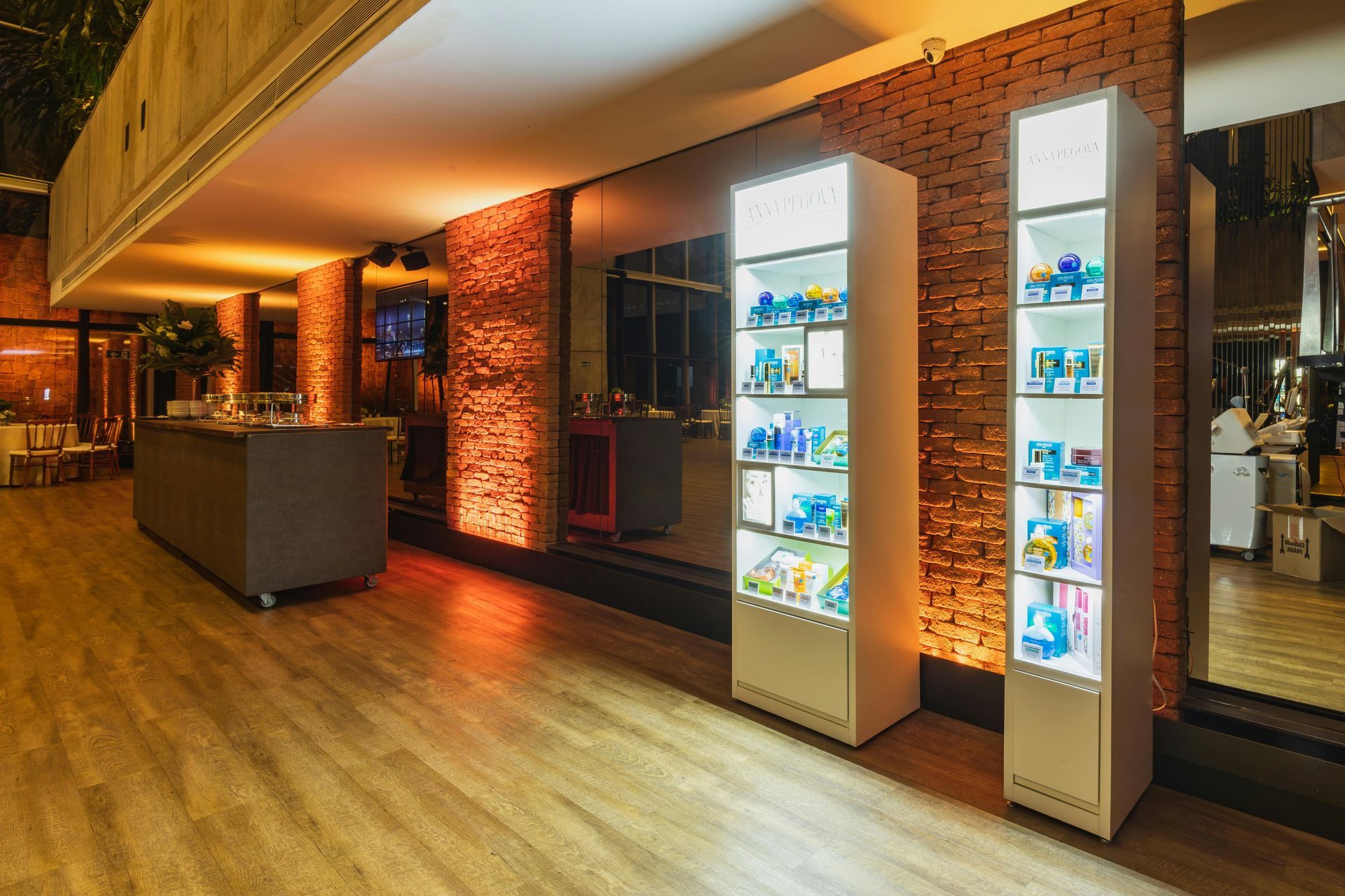 Modern interior with two lit display cases, brick wall backdrop, and wood floors.