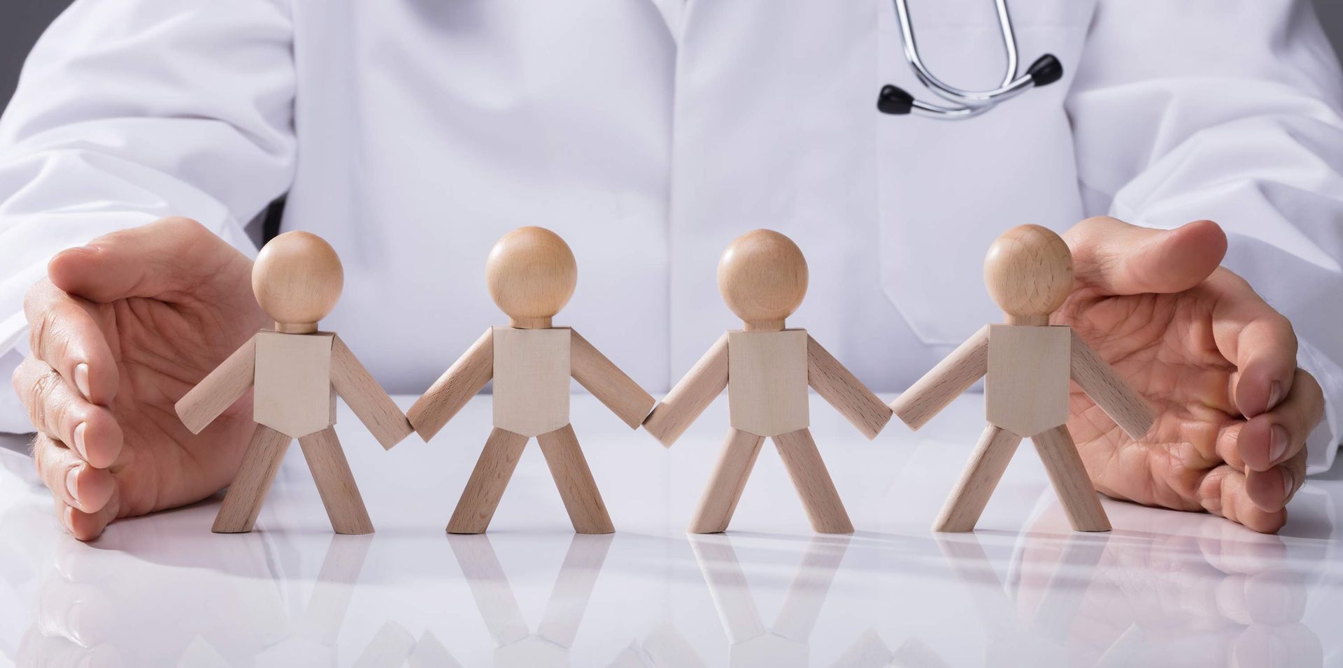 A doctor is holding a row of wooden people holding hands.