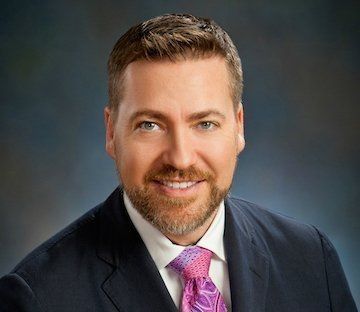 A man in a suit and tie is smiling for the camera.