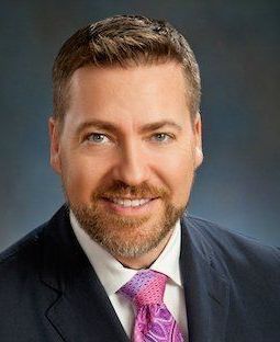 A man in a suit and tie is smiling for the camera.