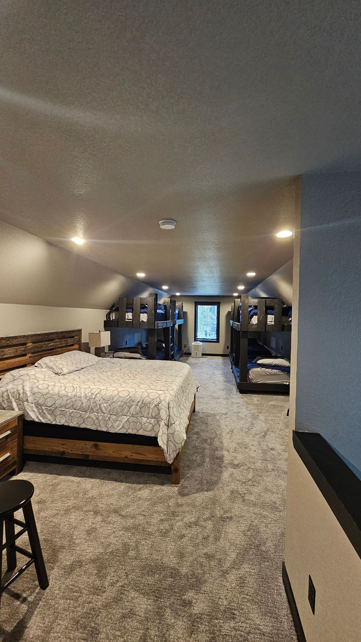 Bedroom with bed, furniture, and recessed lighting in a room with angled walls.