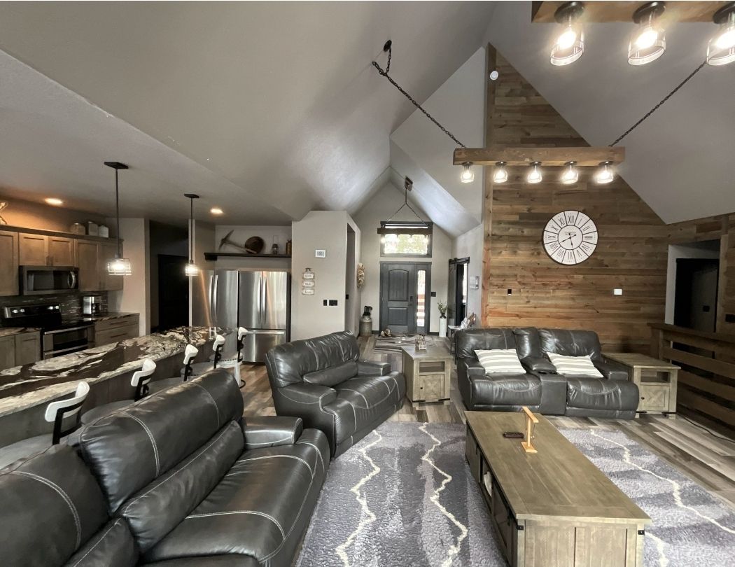 Spacious living room with gray leather sofas, a patterned rug, and wood accent wall.