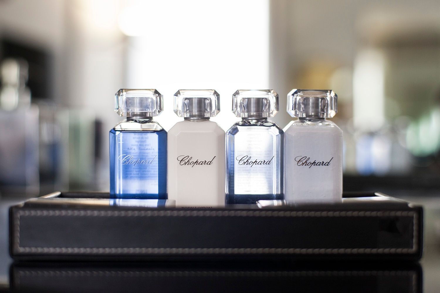 Cuatro frascos de perfume Chopard están en una bandeja.