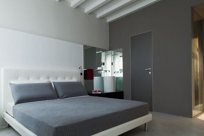 A bedroom with a bed and a bathroom in the background