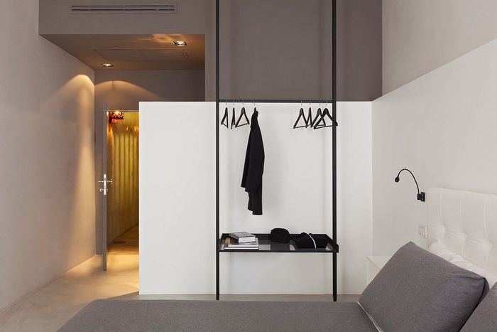 A bedroom with a bed and a shelf with clothes hanging on it