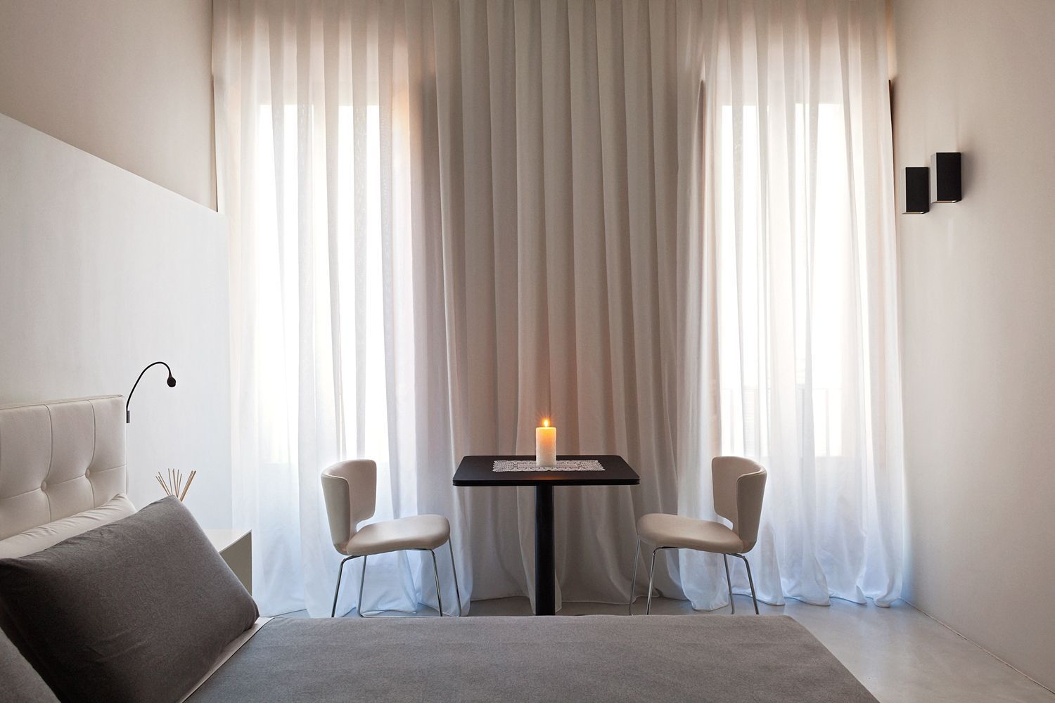 Un dormitorio con dos sillas y una mesa con una vela encima.