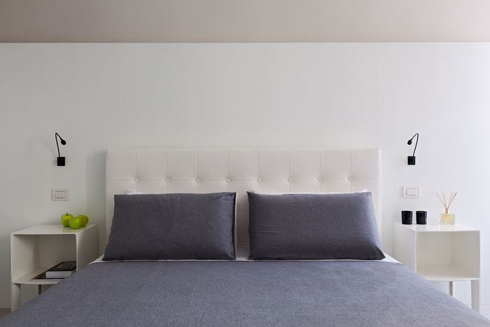 A bed with a white headboard and grey pillows in a bedroom