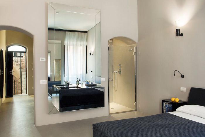 A bedroom with a large mirror on the wall and a walk in shower.