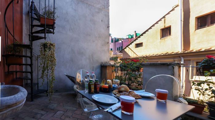 There is a spiral staircase in the background and a table with plates and drinks on it.