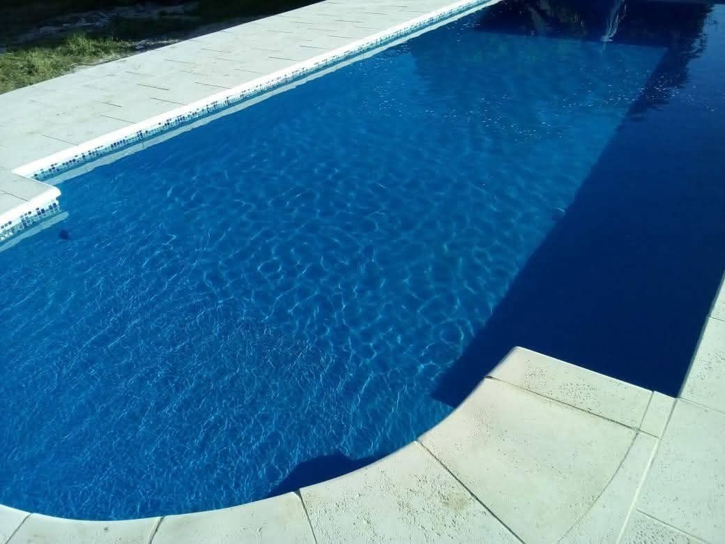 Piscina rectangular de color azul con borde de baldosas de color claro.