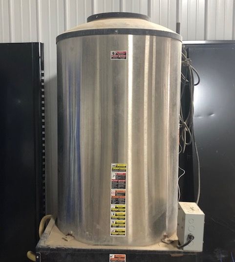 A large stainless steel water heater is sitting on top of a black box.