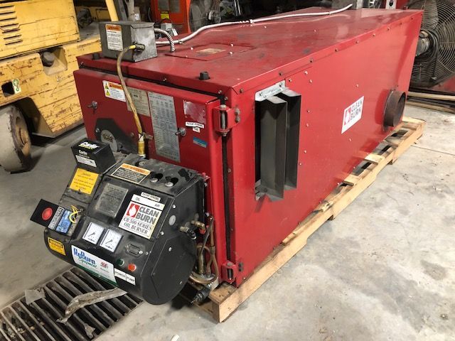A red machine is sitting on a wooden pallet in a garage.
