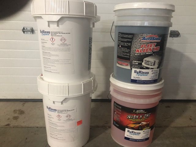 Three buckets of chemicals are stacked on top of each other.