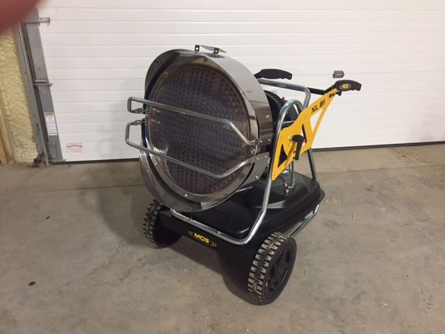 A large fan on wheels is sitting in front of a garage door
